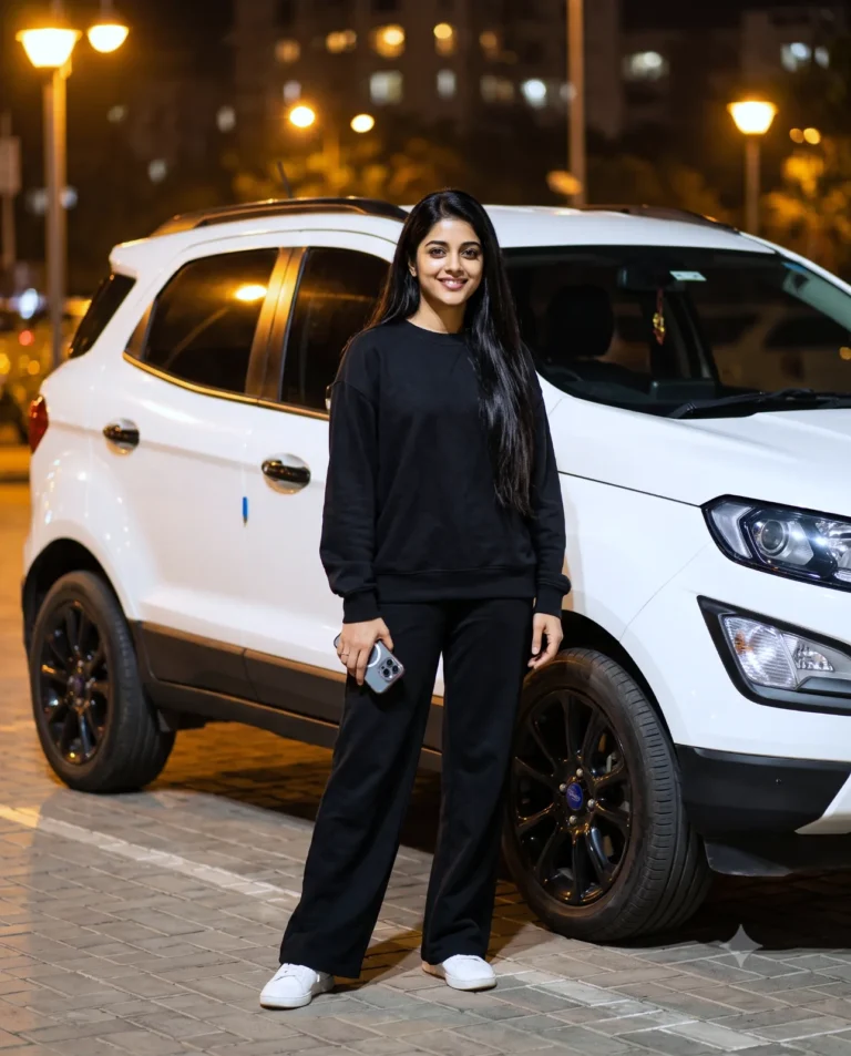 A professional night portrait showing a confident woman standing beside a white luxury SUV under warm streetlamps.